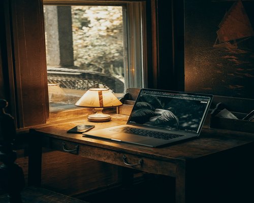 A person resting by reading a physical book under a soft desk lamp