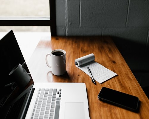 A coffee cup and a notebook placed on an office desk to encourage a break